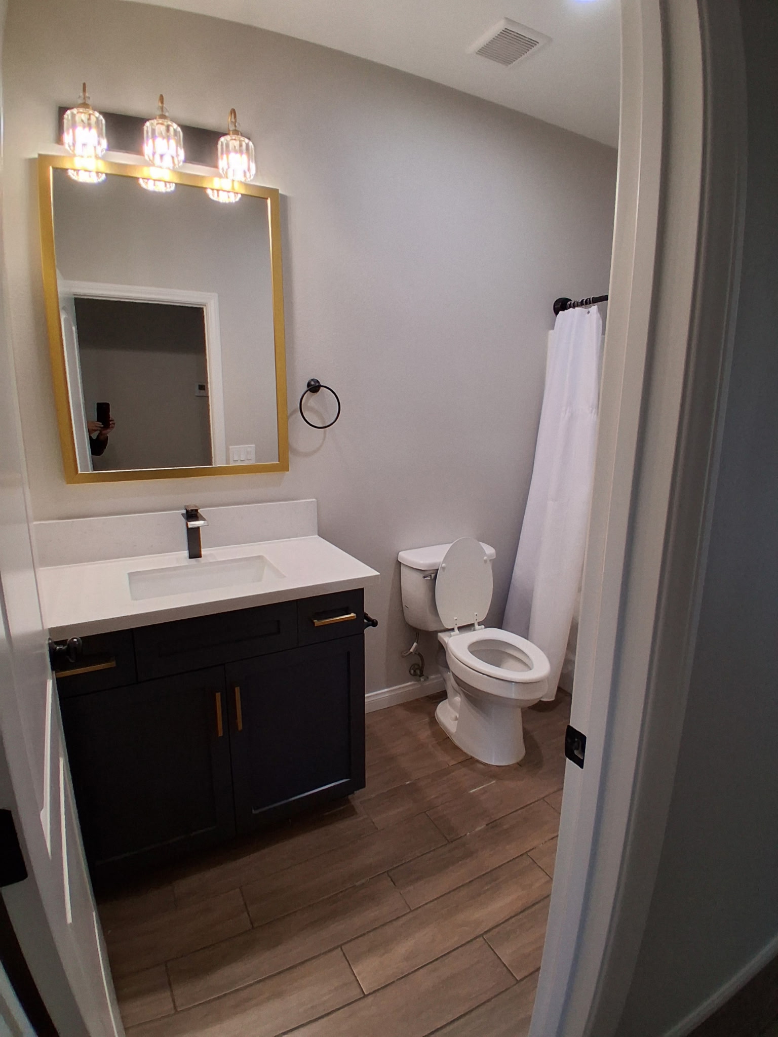 Sparkling clean powder bathroom with navy vanity and gold mirror